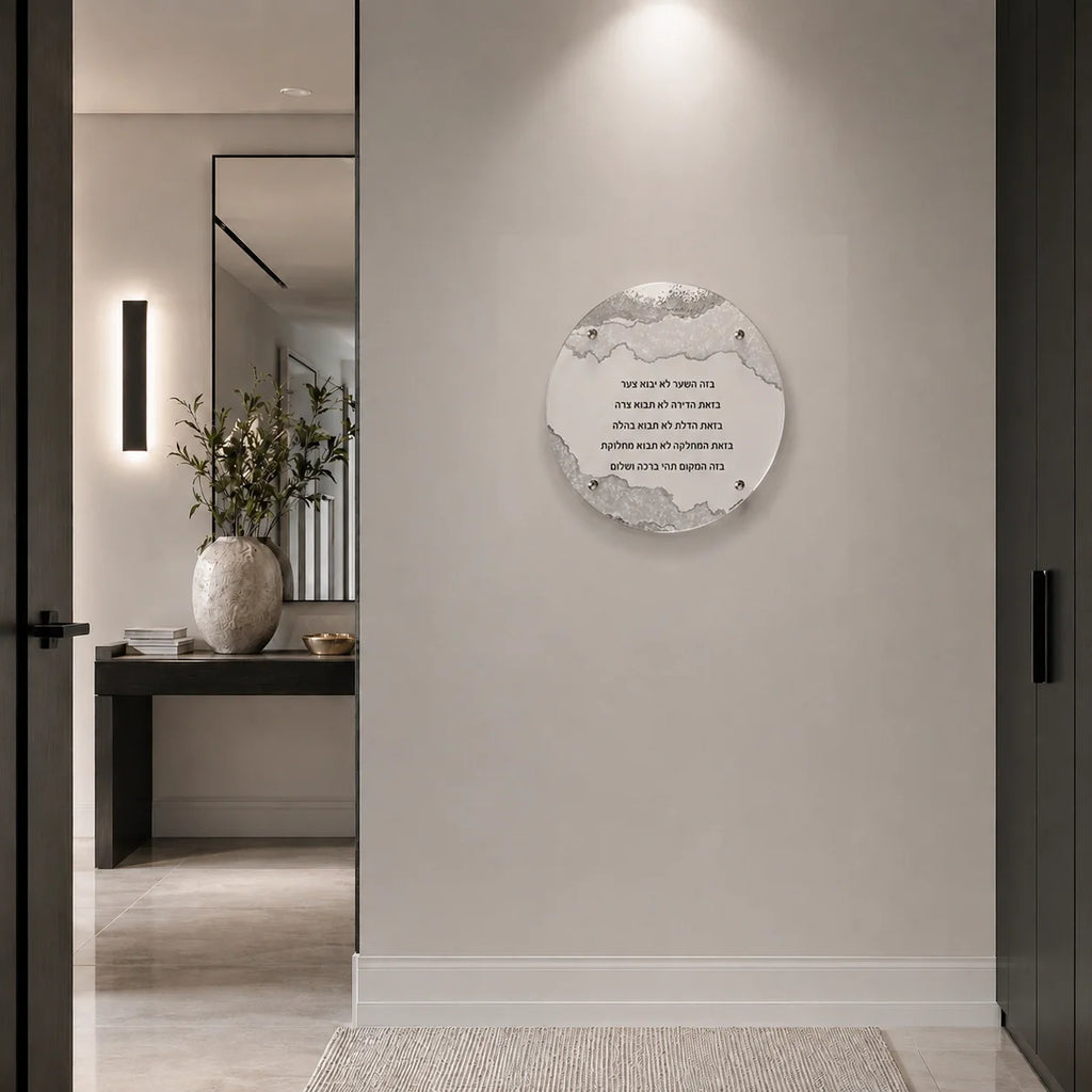 A circular wall art print featuring BIRCHAS HABAYIS displayed on a light beige wall in a modern, minimalist hallway with a mirror and console table visible in the background.