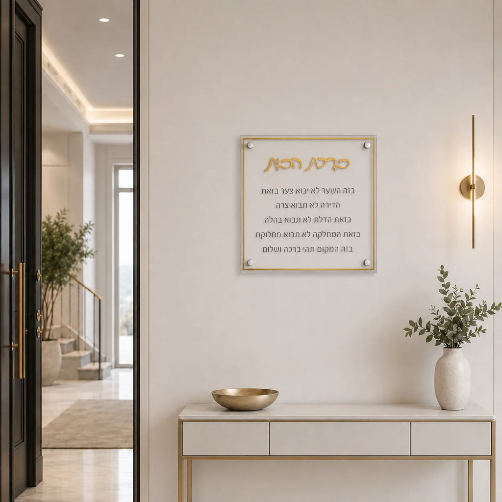 A modern acrylic wall plaque with gold Hebrew lettering and English text, mounted on a white wall in a stylish, contemporary entryway with a console table and vase.