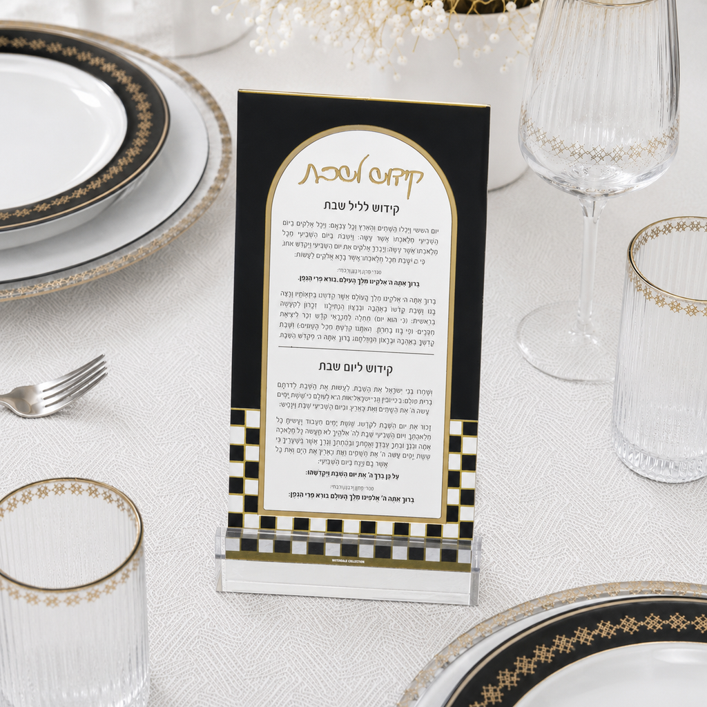 A clear acrylic ONYX KIDDUSH CARDwith a black and gold design, displayed on a white tablecloth surrounded by plates, glasses, and a fork.