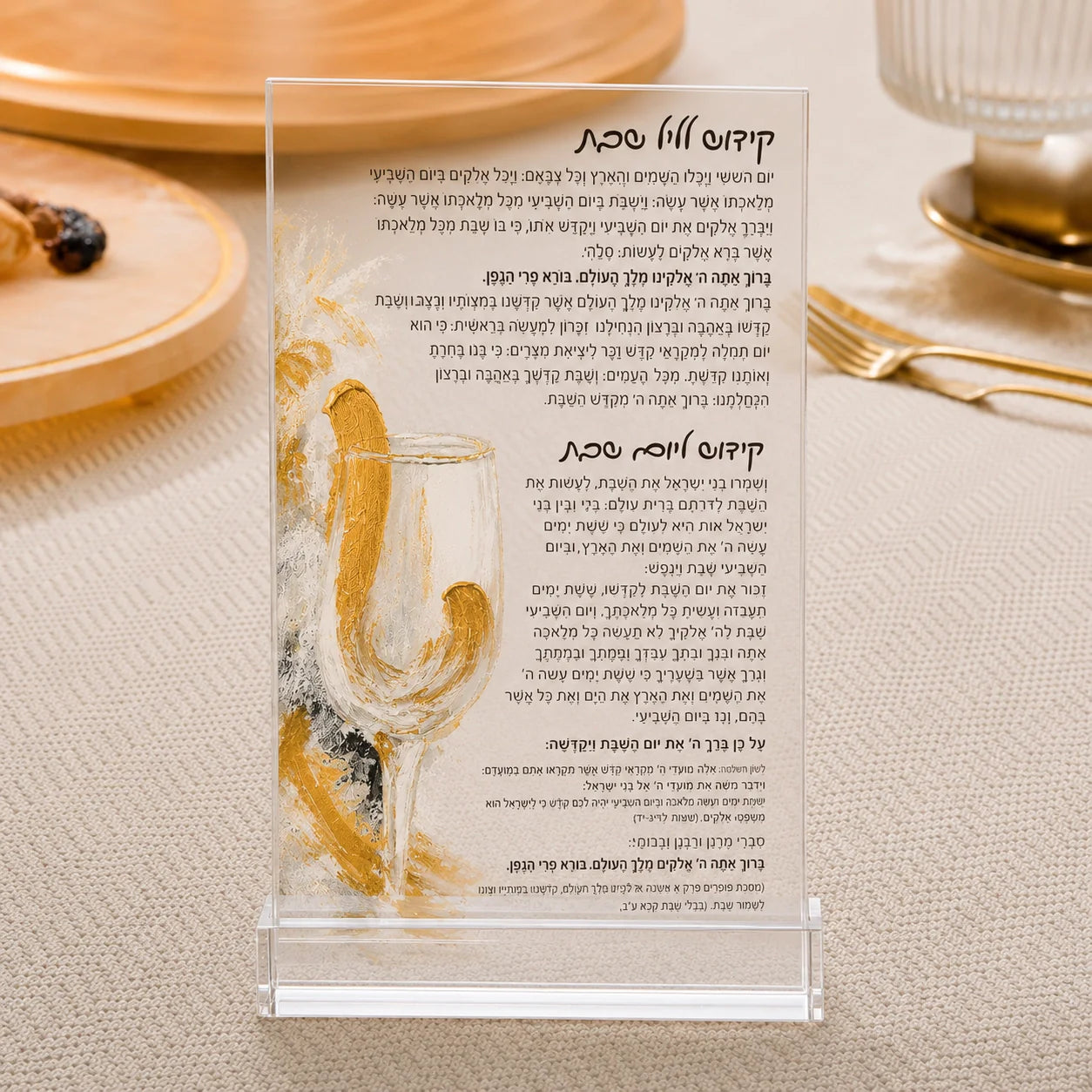 A clear acrylic stand holding a printed Hebrew prayer card, photographed on a beige fabric surface with a blurred plate of food in the background.