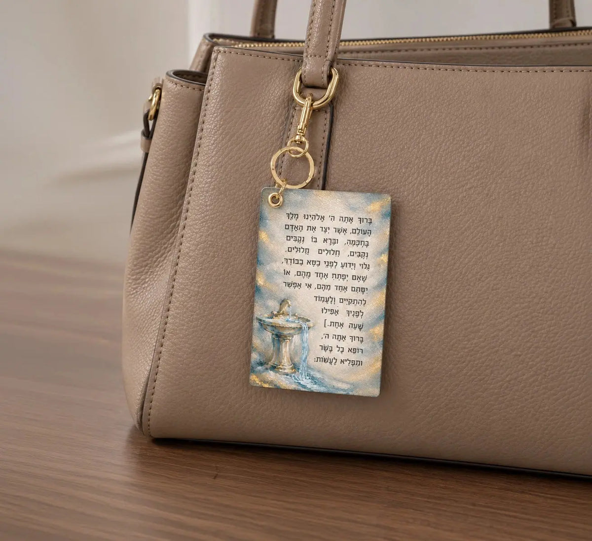 Leather Asher Yatzar keychain with the full bracha in Hebrew beside a painted fountain and flowing water