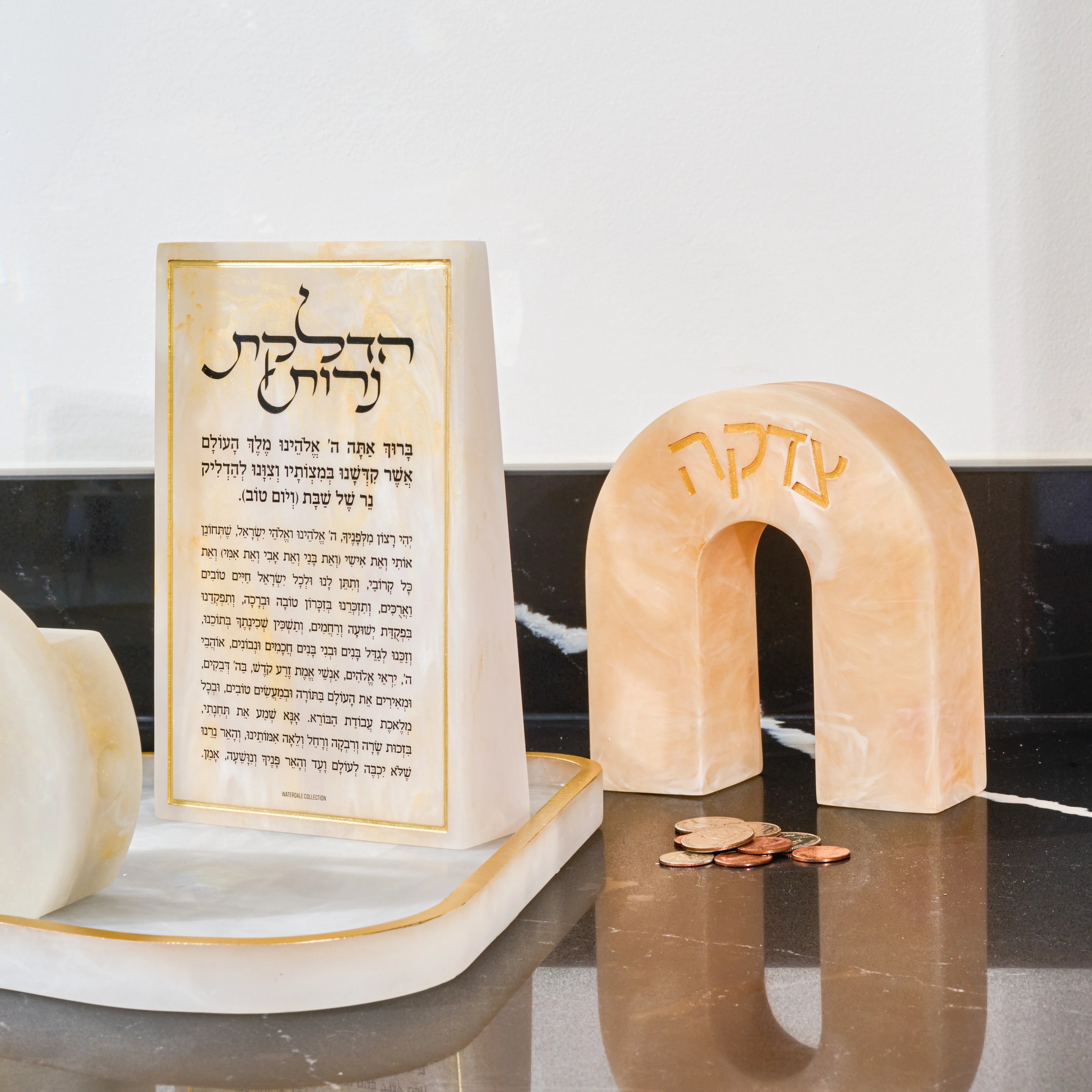Cream resin arch tzedakah box with Hebrew text, displayed near  a resin base with resin brachos block