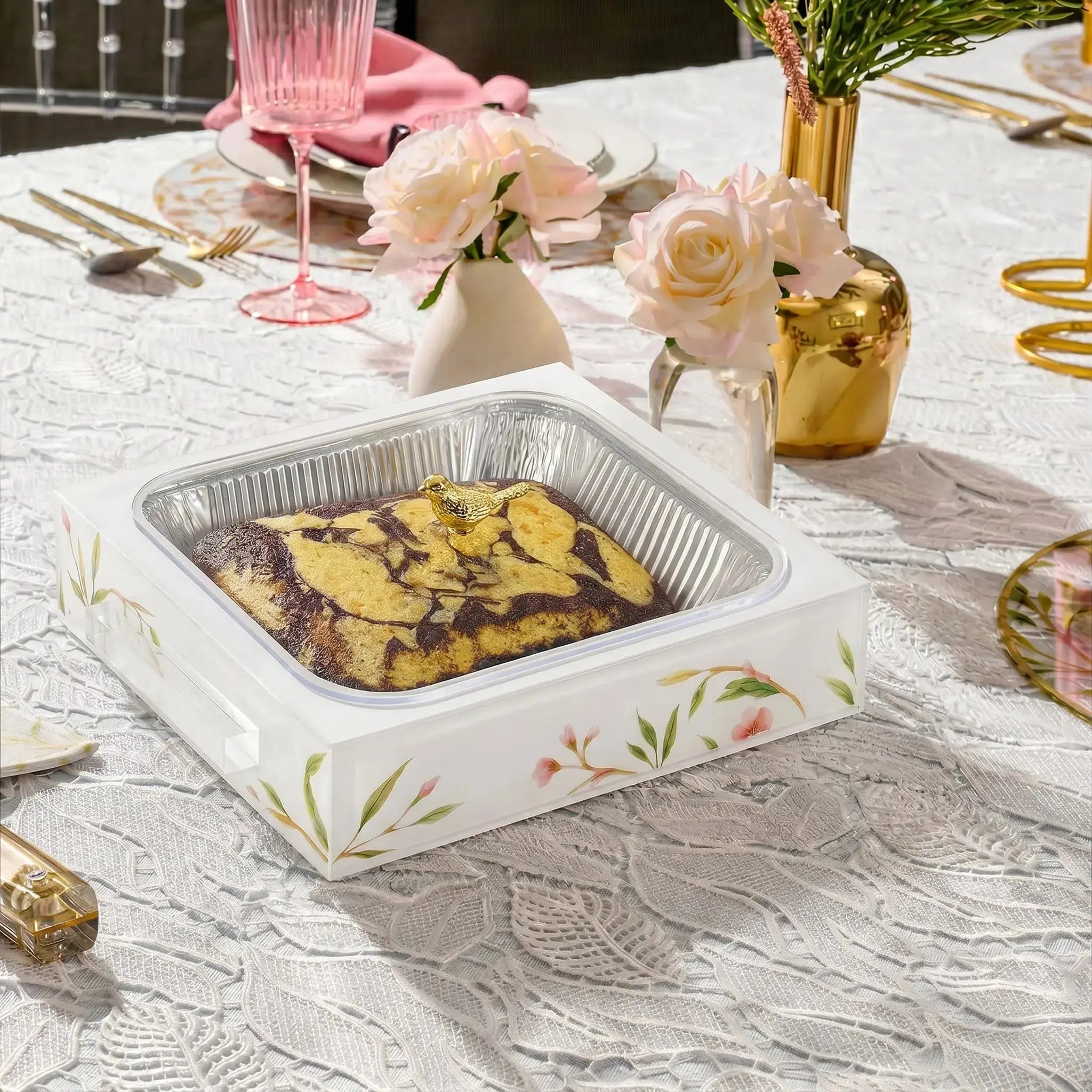 Floral Bird 9x13 pan holder in pearl marble with roasted potatoes, styled on a tabletop with table linens and gold accents.