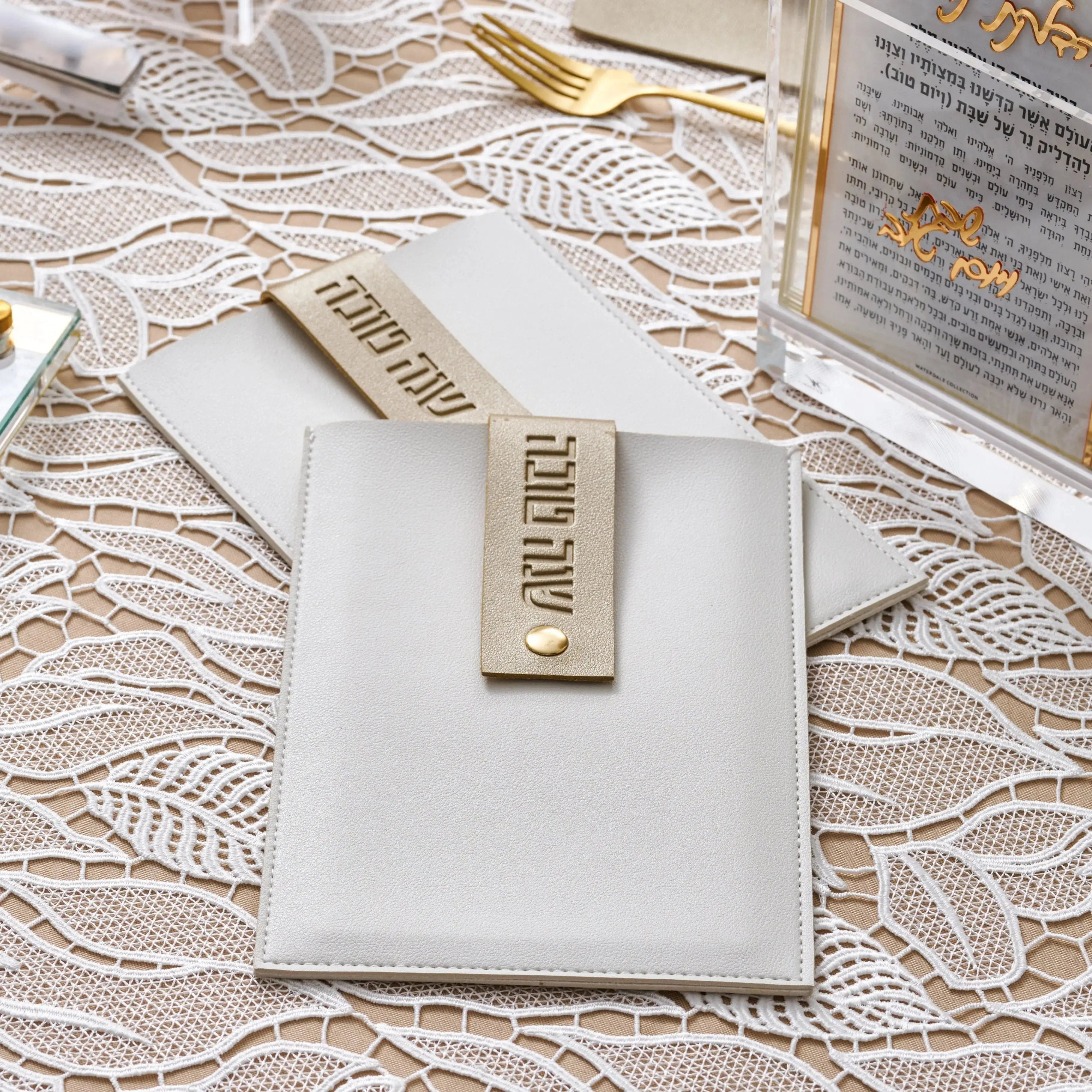 White leather Simanim pouch with lucite card set for Rosh Hashanah and Jewish holidays, displayed on lace background.