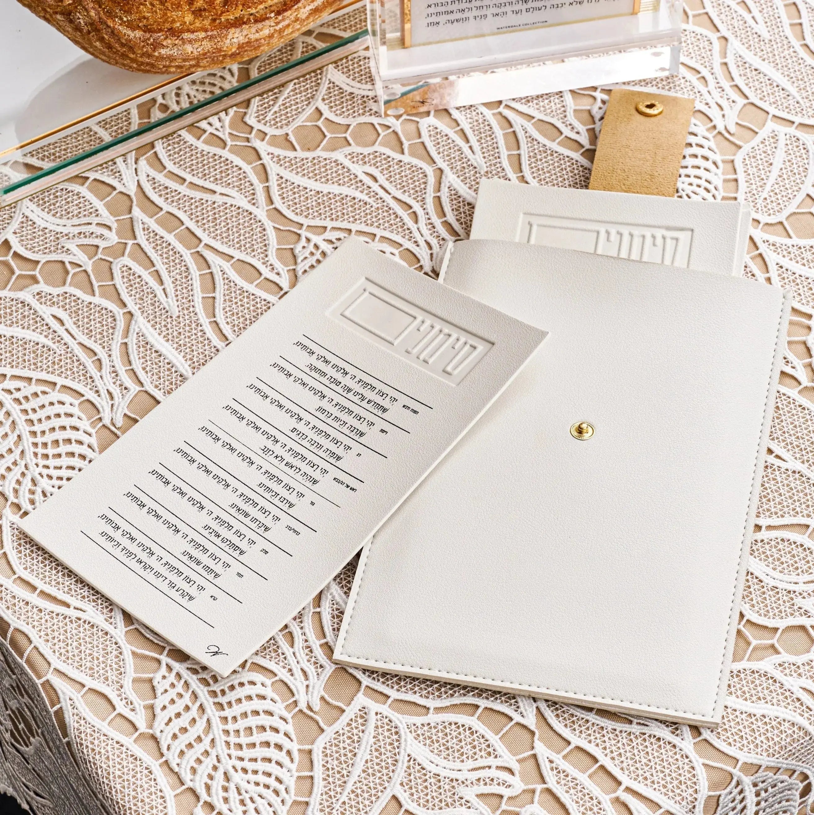 Leather Simanim pouch in tan with white lucite cards displayed on patterned fabric, showing product packaging and contents for Rosh Hashanah.