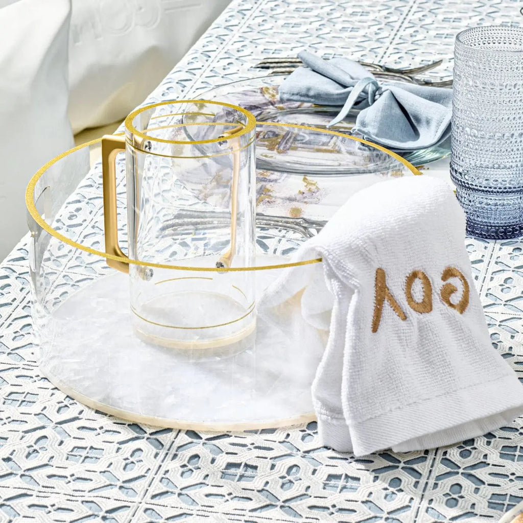 Pearlstone washing bowl and cup set in white marble finish with gold accents, displayed with white linens on decorative background.