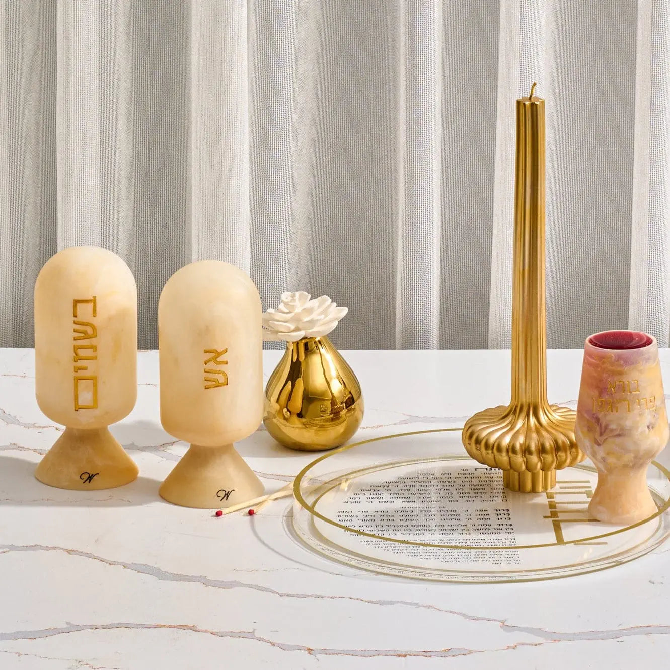Gold resin besamim clove holder with matching brass cloche cover and wooden ball finial, displayed with shabbat candles and ceremonial accessories on marble surface.