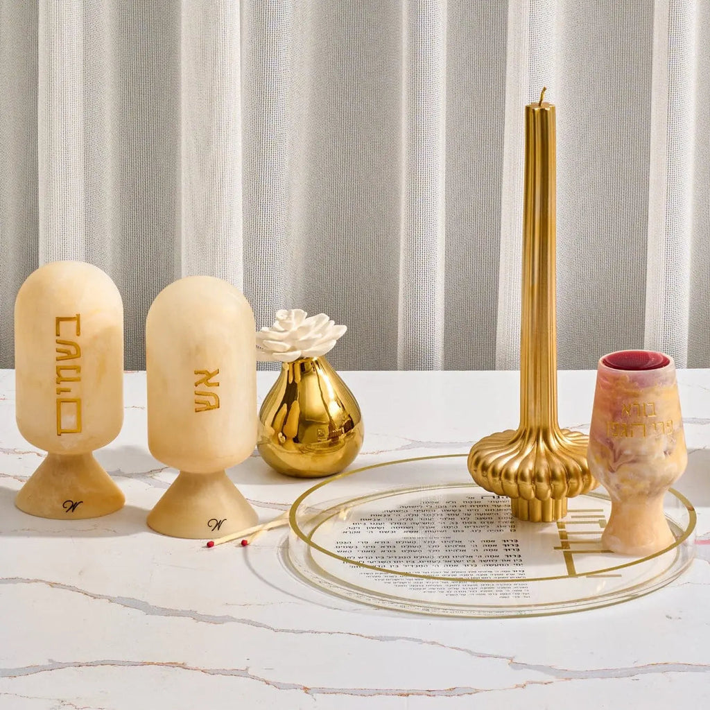 Cream resin Matzah cloche with gold metal accents and matching candle holder, displayed with Shabbat candles on marble surface