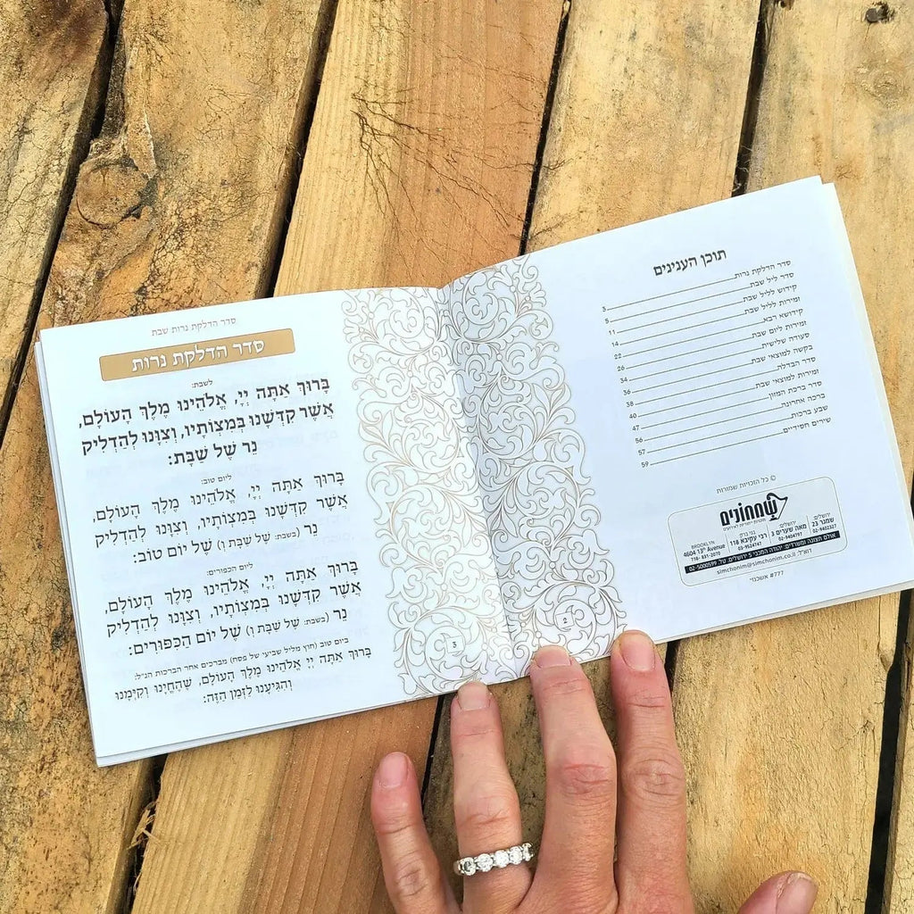 Cream and gold leather softcover bencher set displayed open on wooden surface, showing printed pages and binding details for Birchat Hamazon.