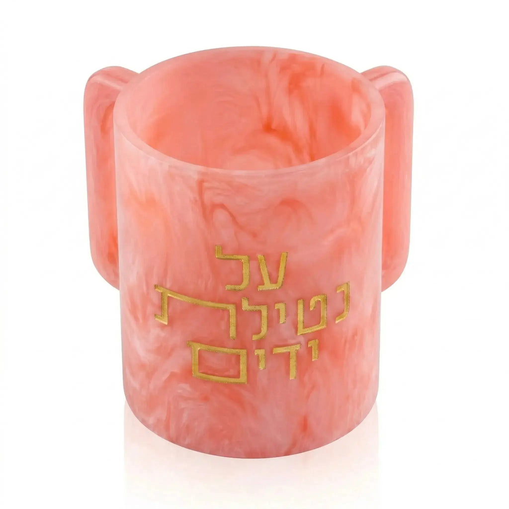 Coral pink resin Al Netilas Yadayim washing cup with gold Hebrew text detailing, featuring curved handles on sides for ritual hand washing.