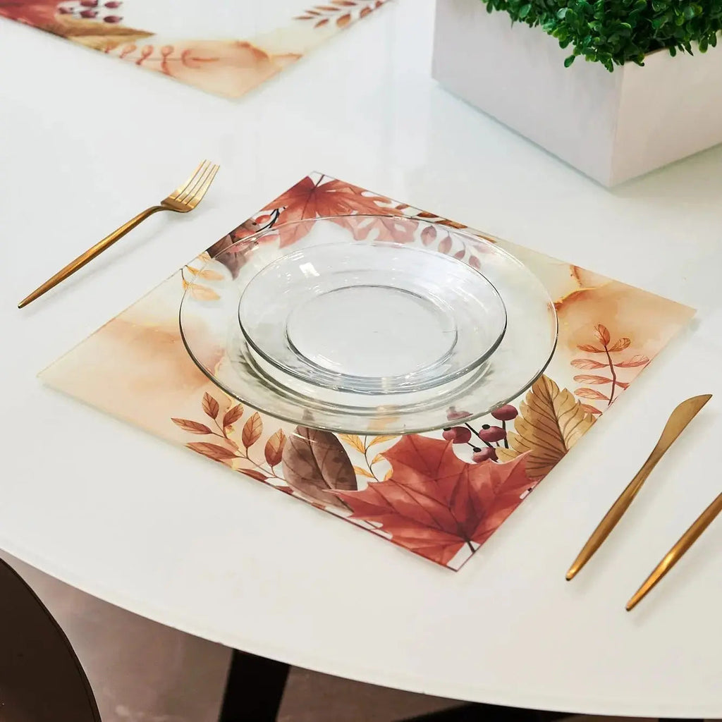 Autumn Chargers by Waterdale Collection featuring warm-toned watercolor leaves in burgundy and gold on white linen, styled with clear glass charger and gold flatware on white round table.