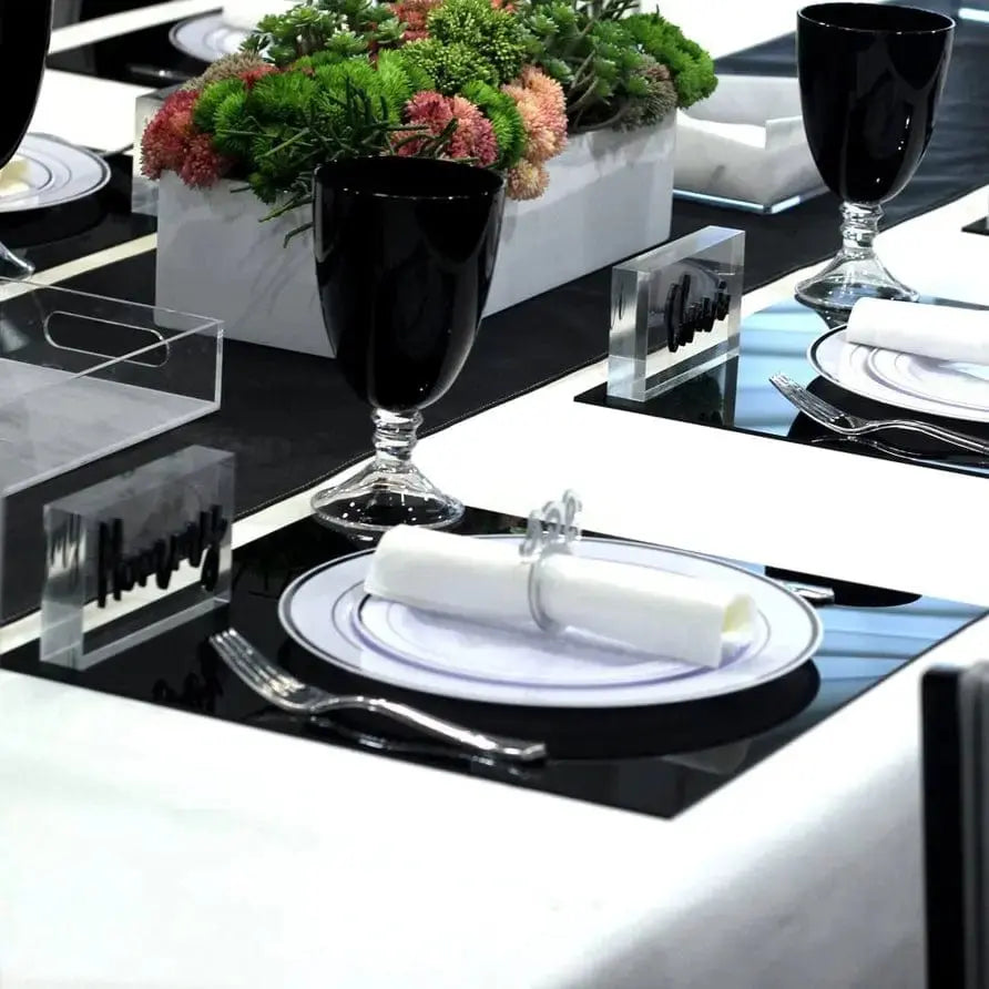 Black charger plates from Waterdale Collection arranged on a formal dining table with white linens and place settings.