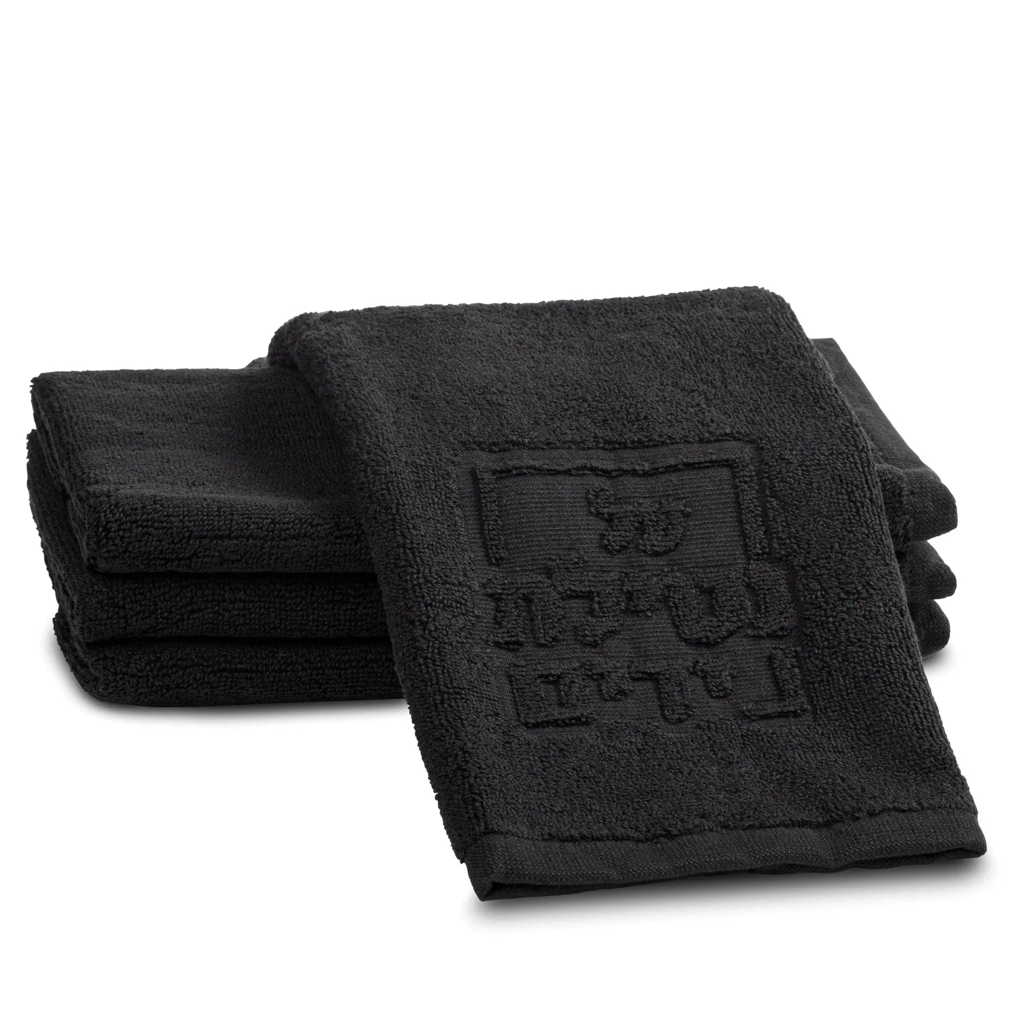 Black embossed finger towel from Waterdale Collection for netilas yadayim hand washing, folded stack display.