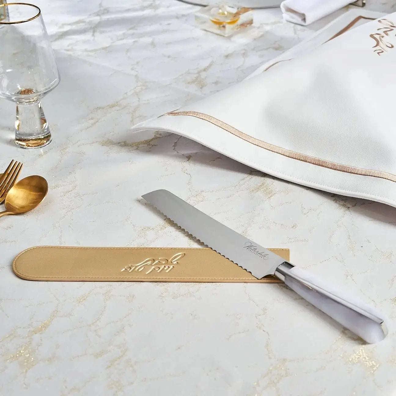 Waterdale Collection bread knife with serrated blade and wooden handle displayed on marble surface with table setting and gold accents.