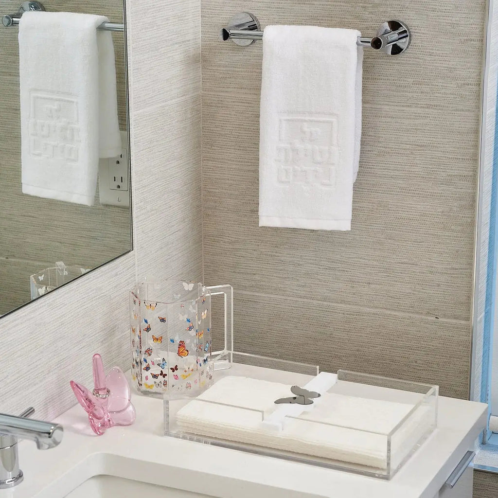 Butterfly Paper Towel Holder in white ceramic displayed on a bathroom vanity with towels and bathroom accessories nearby.