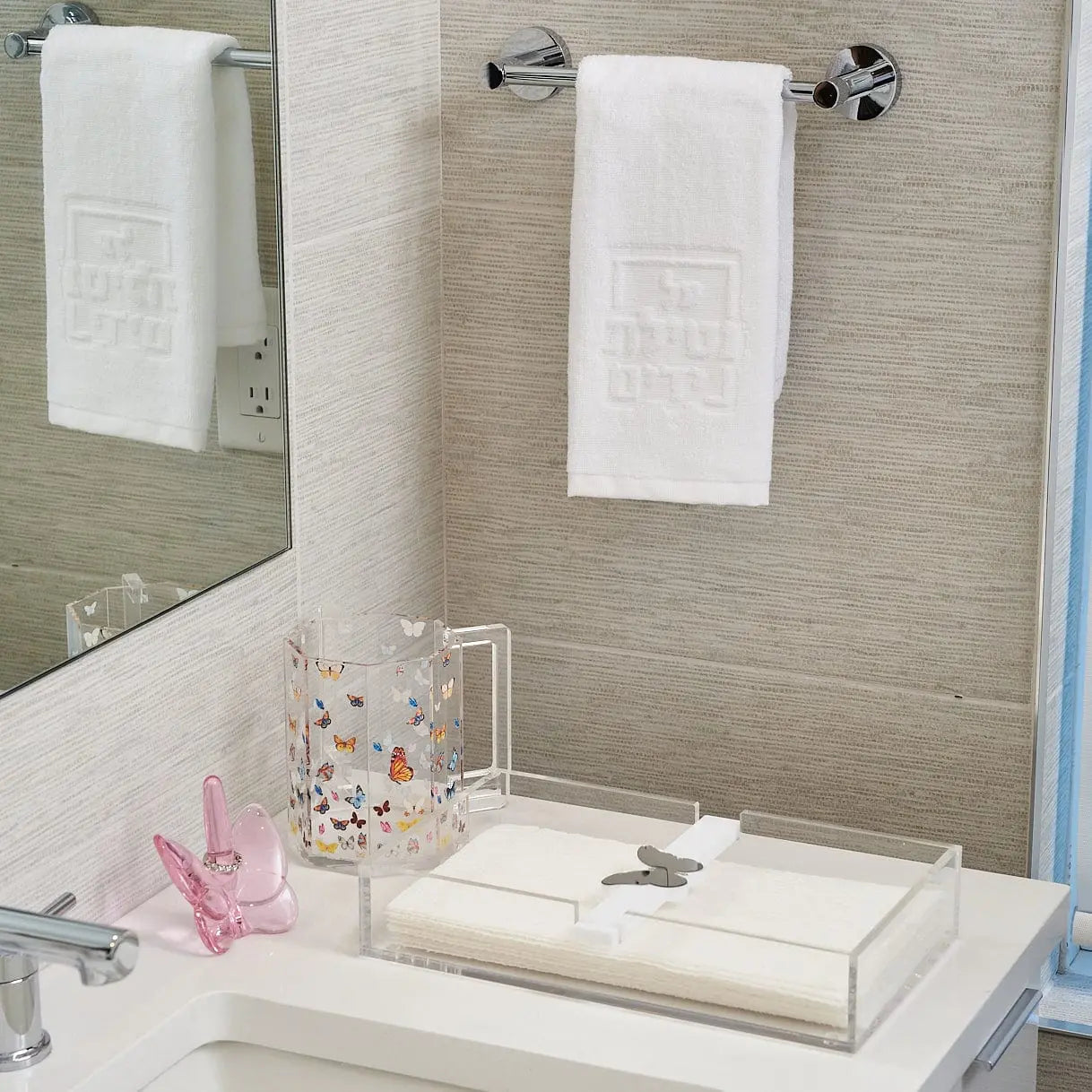 Butterfly Paper Towel Holder in white ceramic displayed on a bathroom vanity with towels and bathroom accessories nearby.