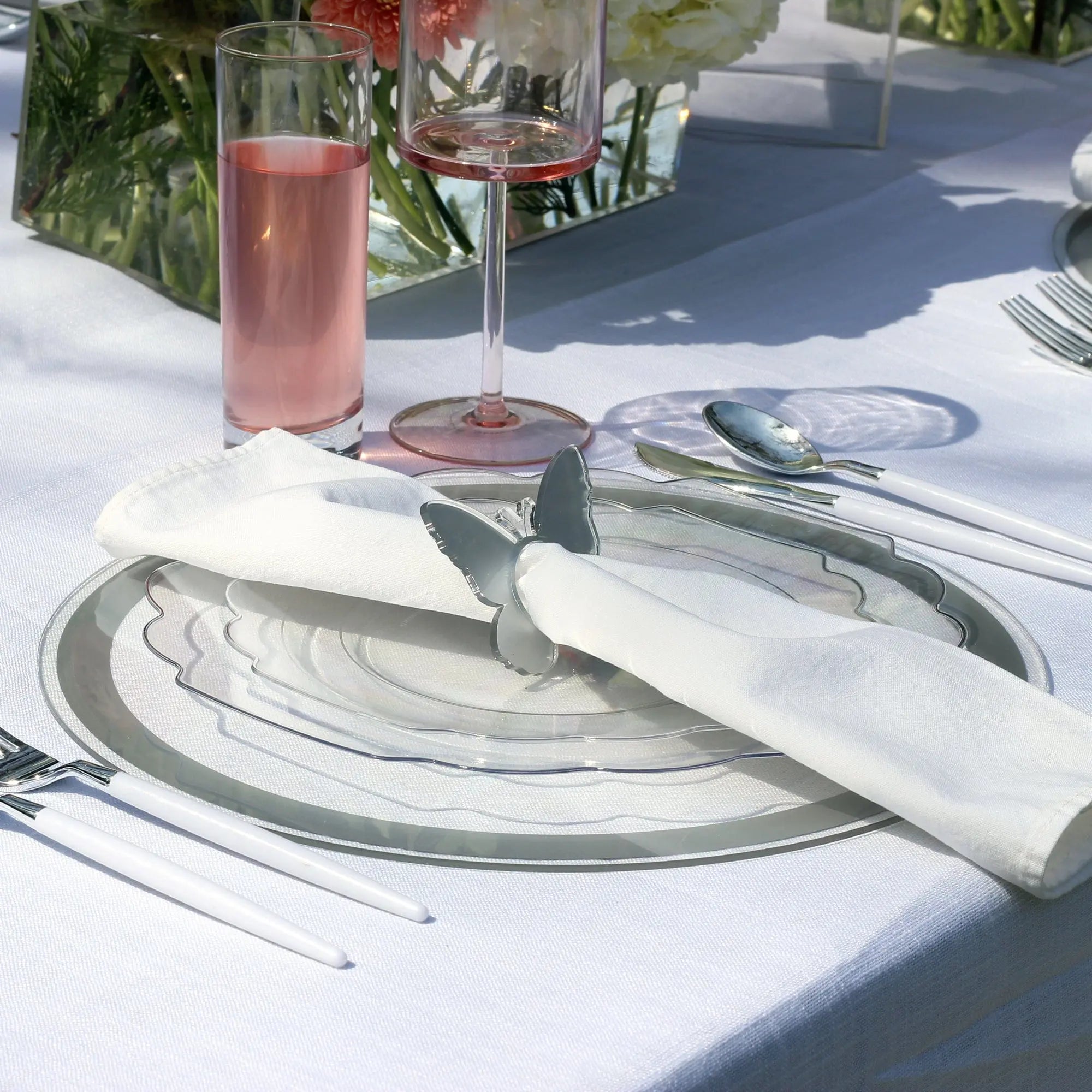 Classic silver-bordered charger plate with black accent detailing, displayed at an elegant table setting with glassware and place card.
