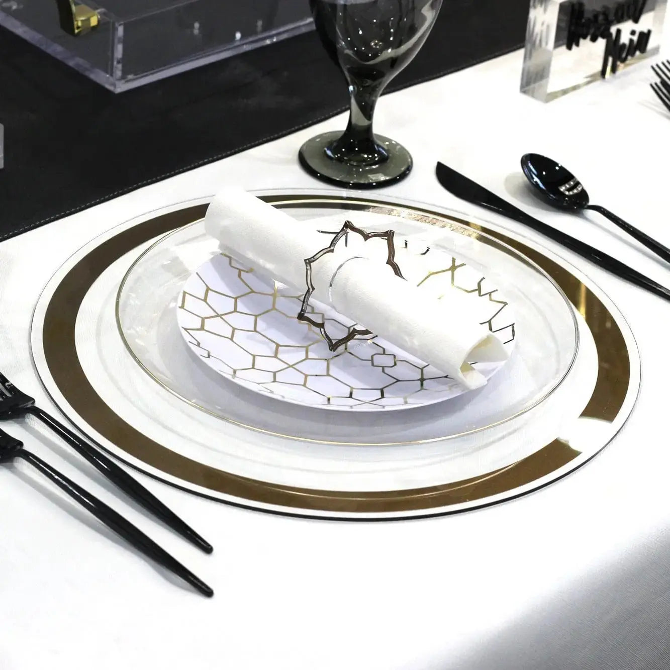 Classic silver-bordered charger plate with delicate blue design, placed on white table setting with black cutlery and stemware.