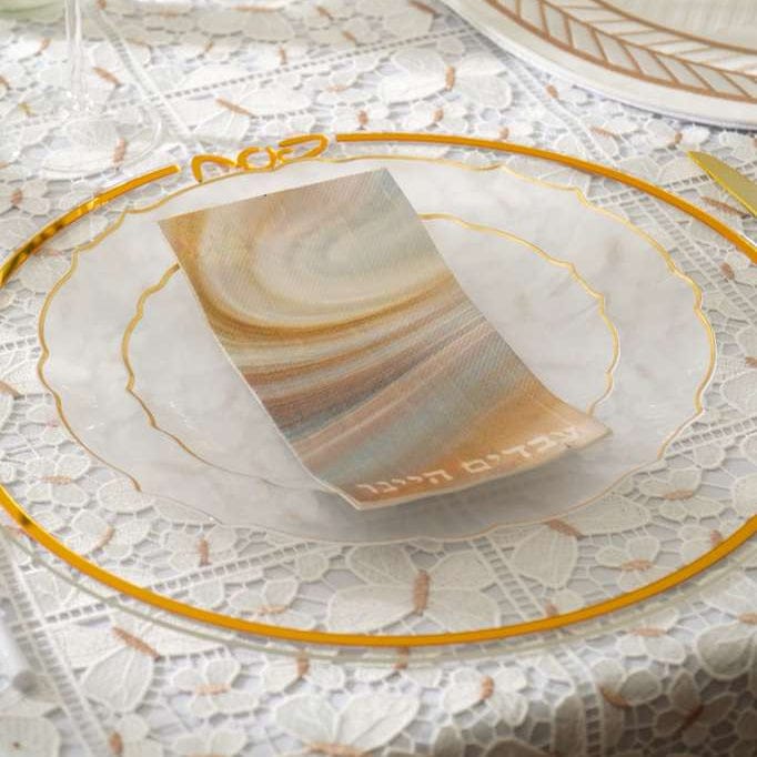 Decorative table setting with a lace tablecloth, gold-rimmed plates, and a card on a marble surface.