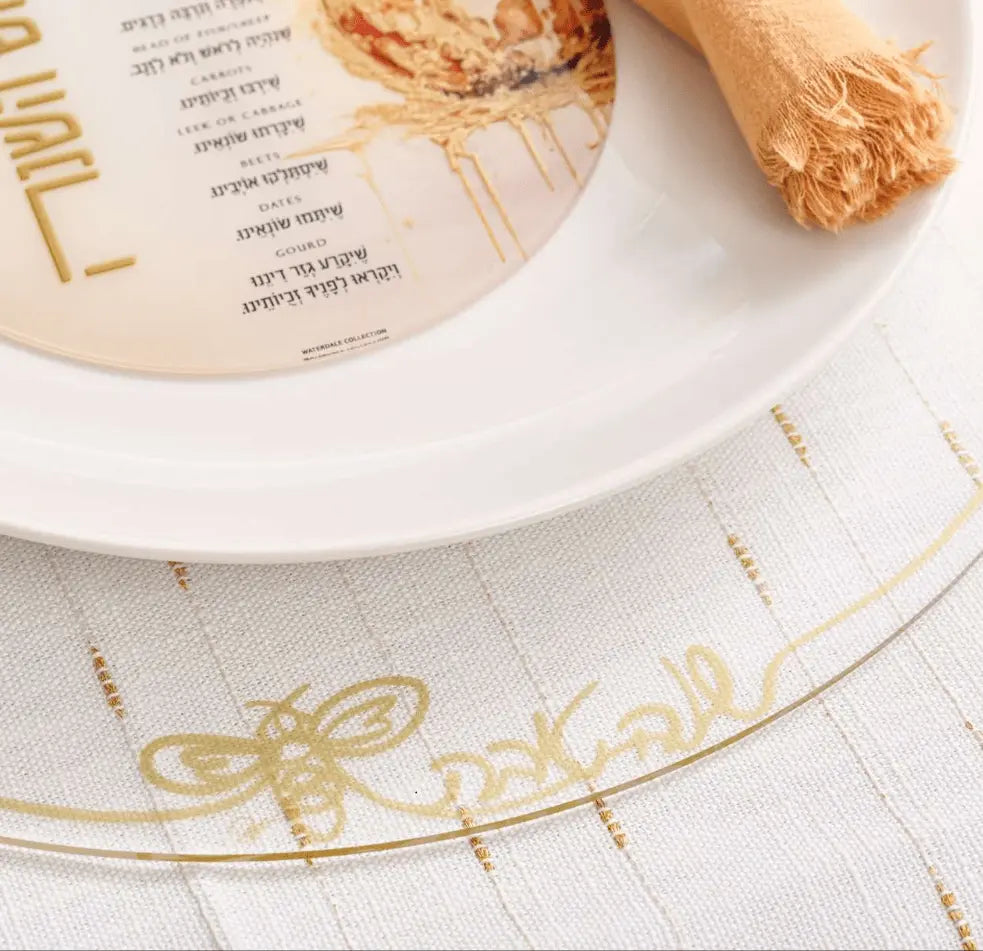 Classic Rosh Hashana charger plates with delicate gold design on white ceramic, featuring silver border detail and traditional holiday table setting styling.