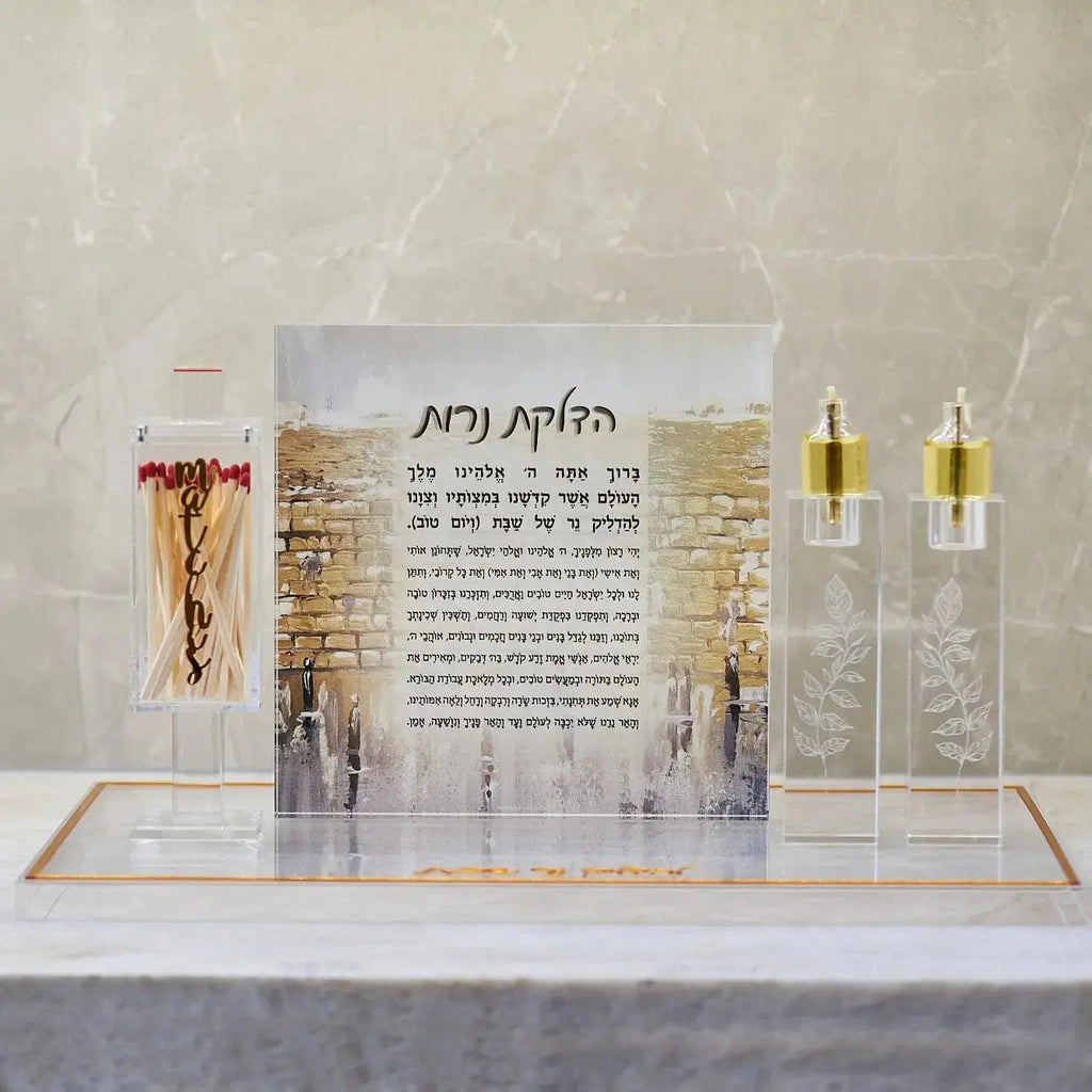 Engraved crystal candlesticks with gold-toned holders displayed on white marble base with matching accessories for Shabbat candle lighting.