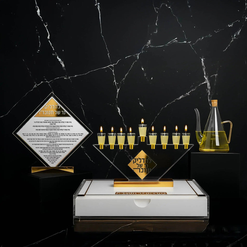 Glass oil jug by Waterdale Collection displayed with gold Hanukkah candles and marble base on black background.