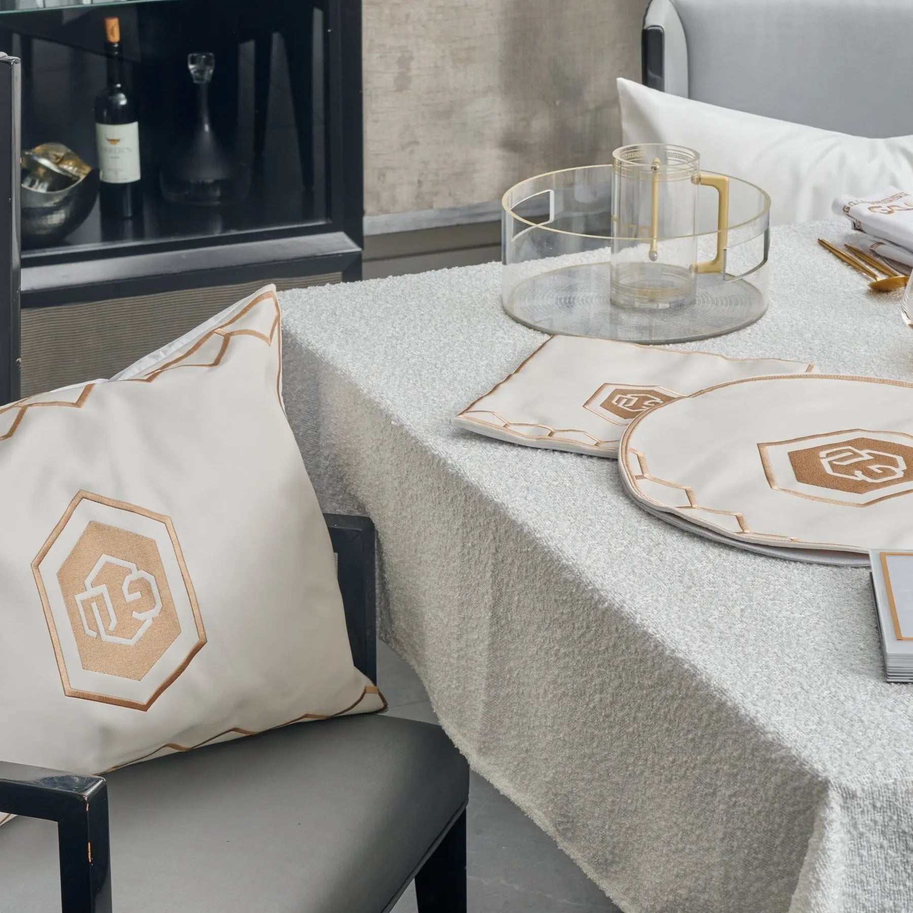 Hexagon Pesach set with white linen tablecloth, matching pillow, and gold geometric tableware arranged on table with leather accents