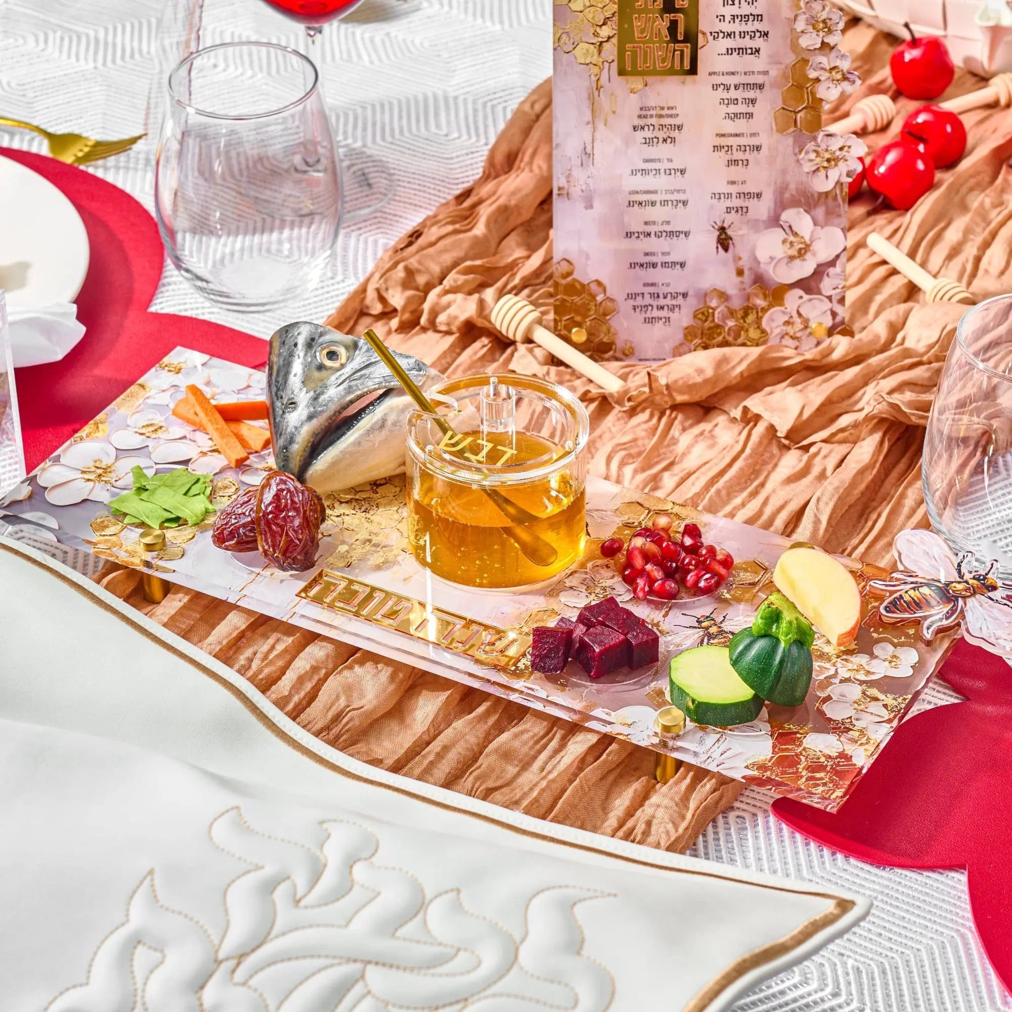 Honeycomb Simanim tray with painted flowers, fish, and holiday symbols arranged with honey, pomegranate, and apples for Rosh Hashanah