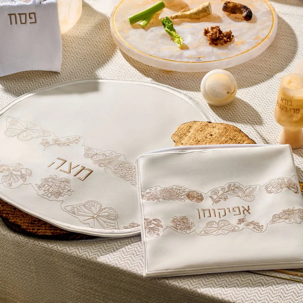 Inlay Floral Pesach Set by Waterdale Collection featuring white leather plates with gold and silver inlay details arranged on a table with matzah and Passover items.