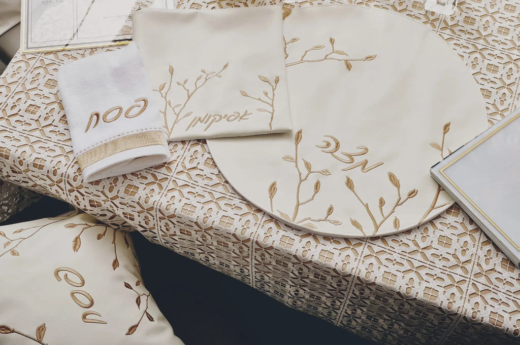 Leaf Pesach Set in gold and white leather with delicate botanical leaf design on cream tableware, displayed on natural linen.