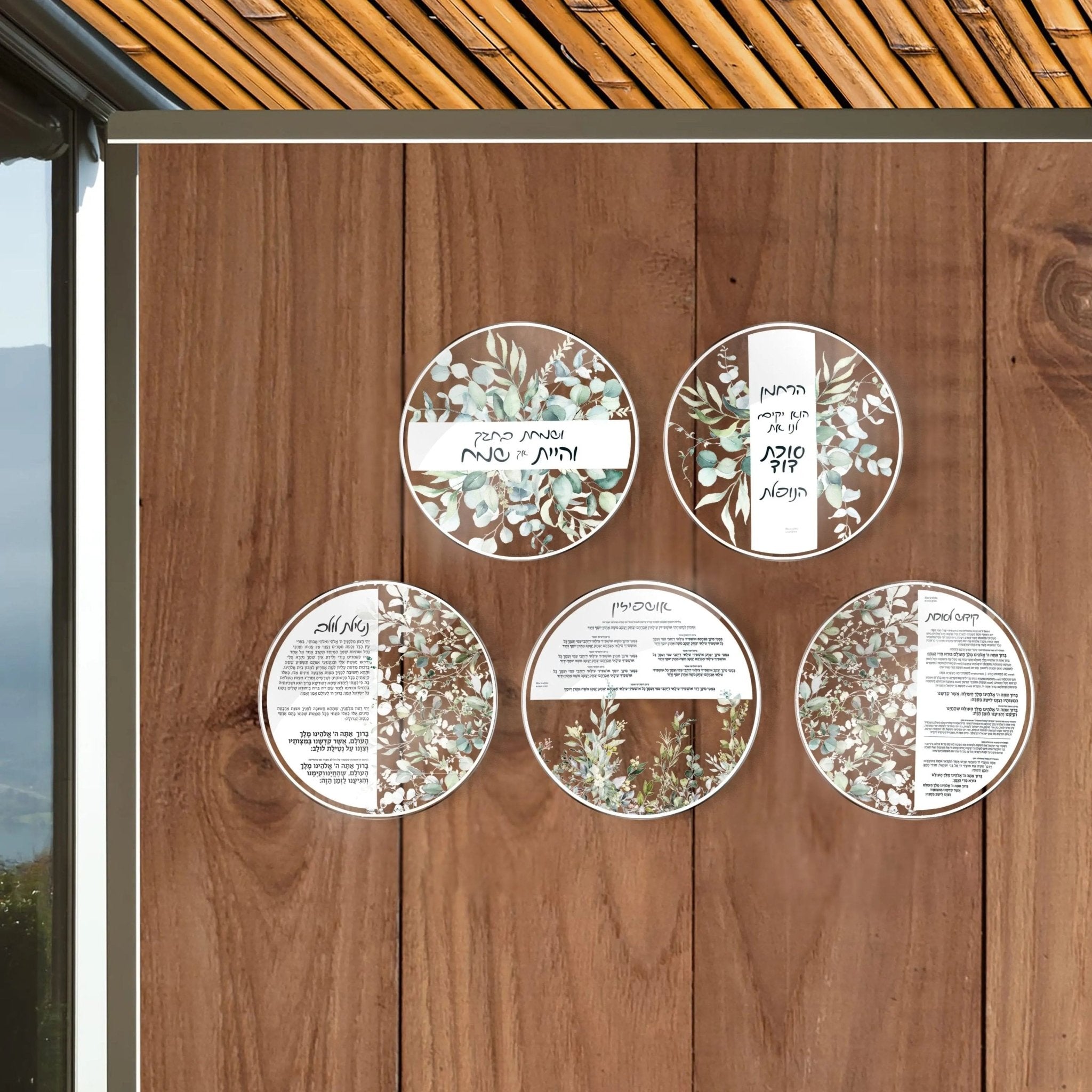 Five circular Leaf Sukkah Decorations from Waterdale Collection arranged on wooden surface, featuring white and natural leaf designs for Sukkot holiday decor.