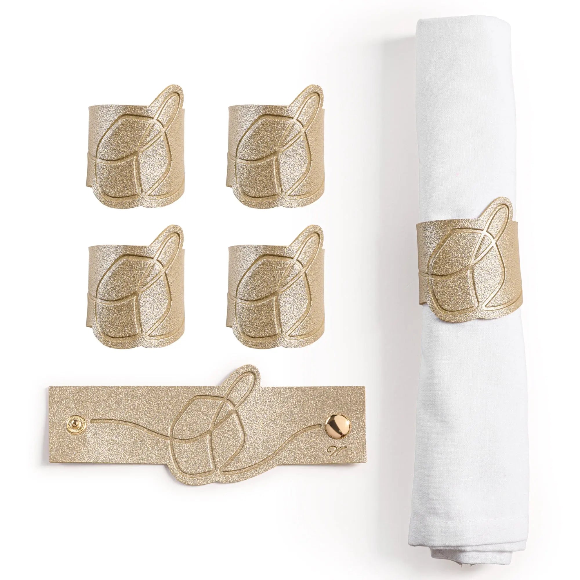 Tan leather dreidel napkin rings arranged with a rolled white napkin, featuring Jewish holiday table decor for Chanukah dining.