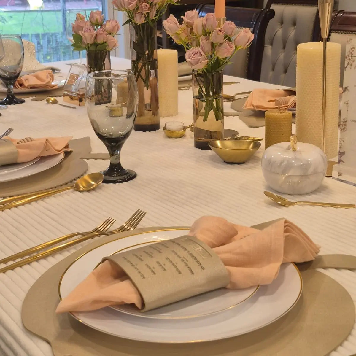 Tan leather Simanim napkin wrap holding a folded napkin on a white plate at a formal dinner table setting with gold accents