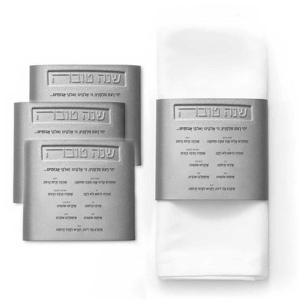 Leather Simanim napkin wraps in silver and gold displayed on folded white napkins, showing elegant napkin ring designs for holiday table settings.