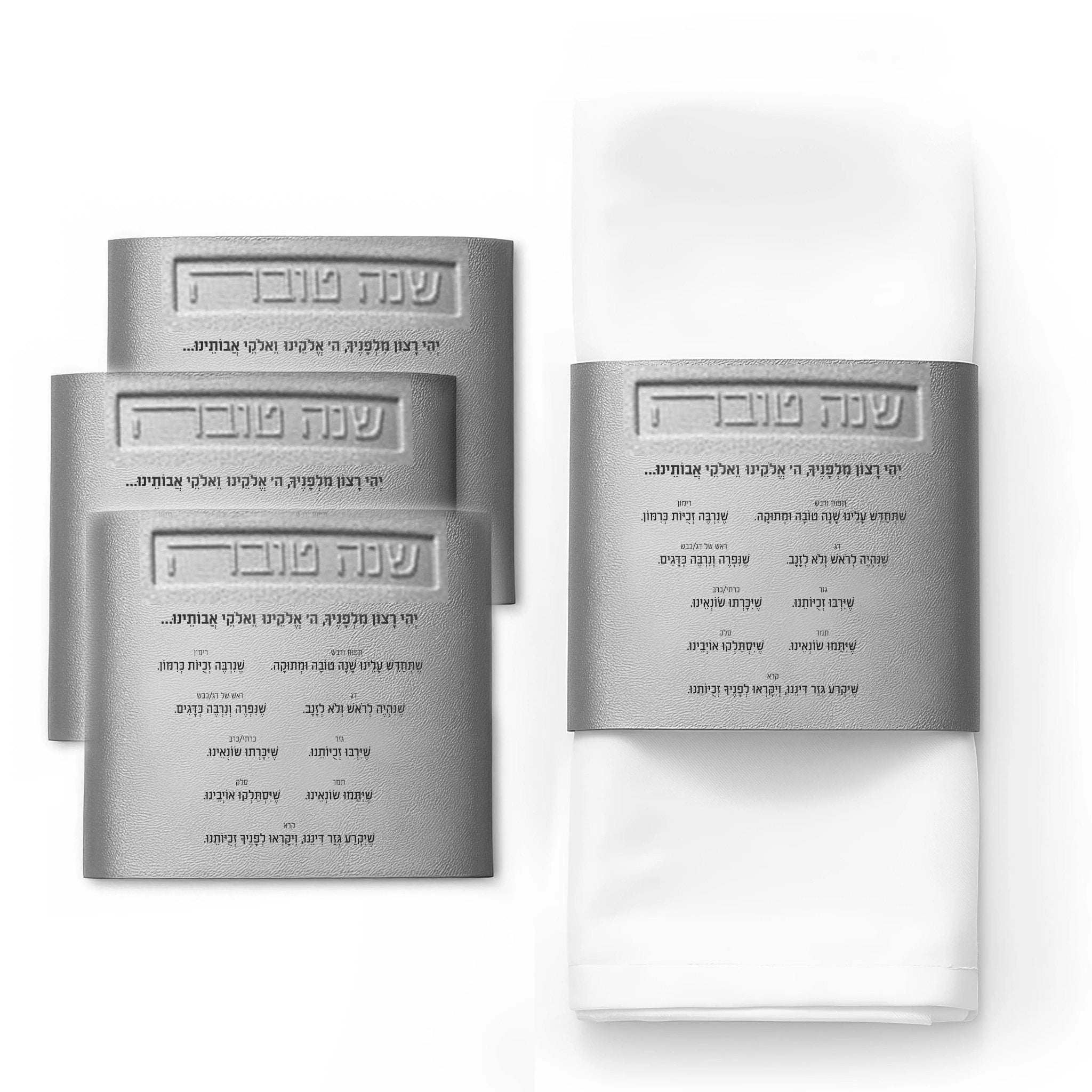 Leather Simanim napkin wraps in silver and gold displayed on folded white napkins, showing elegant napkin ring designs for holiday table settings.