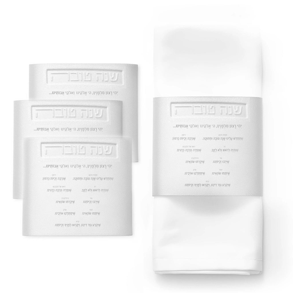 Leather simanim napkin wraps in silver and gold displayed on folded white napkins, showing elegant tabletop styling options.
