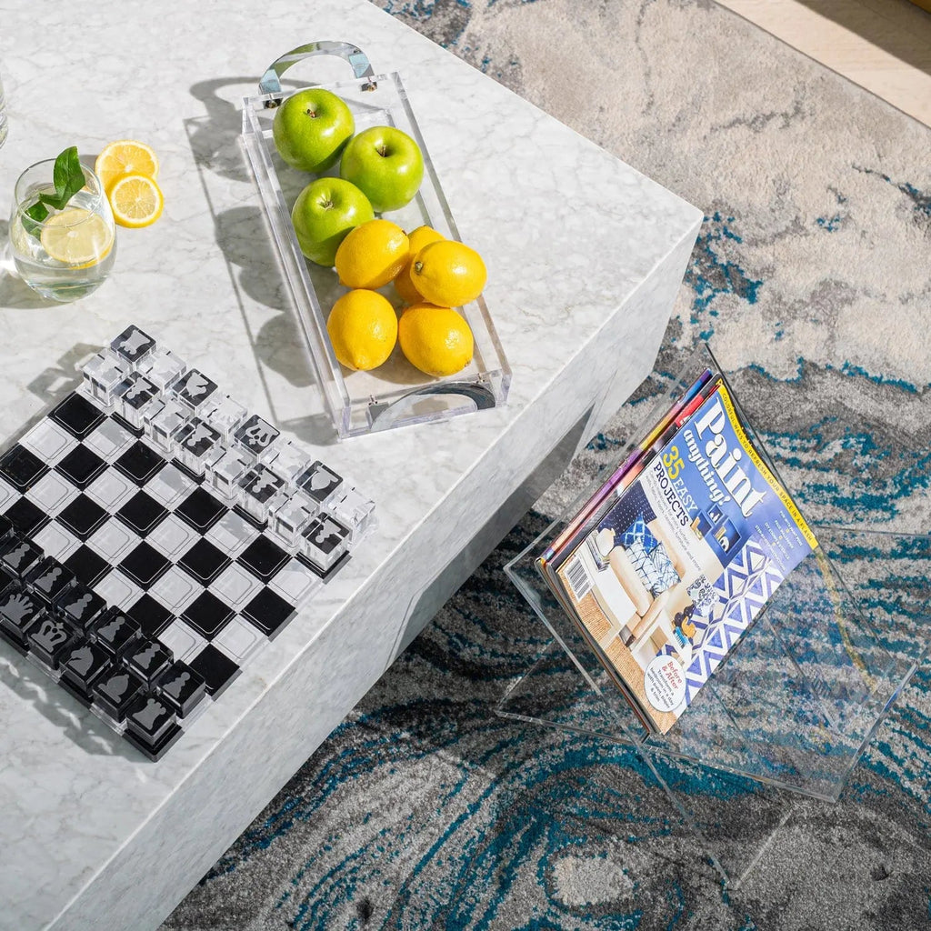 Luxe bread tray in polished metal with gold and green serving pieces displayed on marble surface, styled with chess set and decorative items.