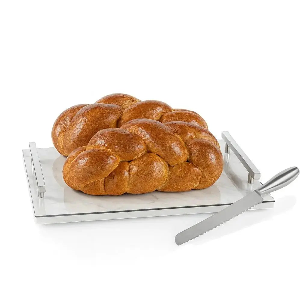 Marble Challah Board by Waterdale Collection with fresh braided loaf and silver knife on white and gold surface.