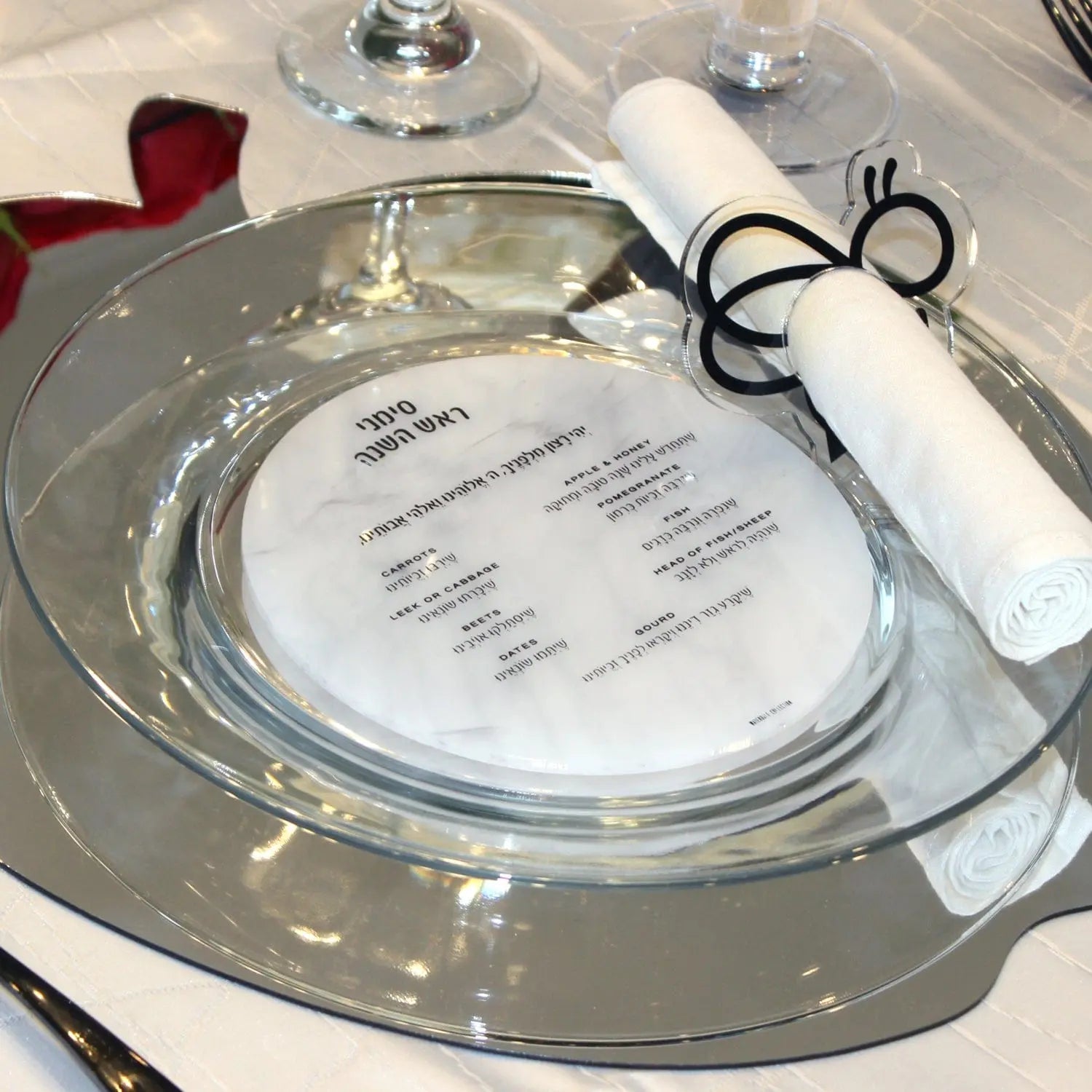 Marble Round Simanim Card in clear lucite with printed text, displayed on table setting for Rosh Hashanah holiday observance.