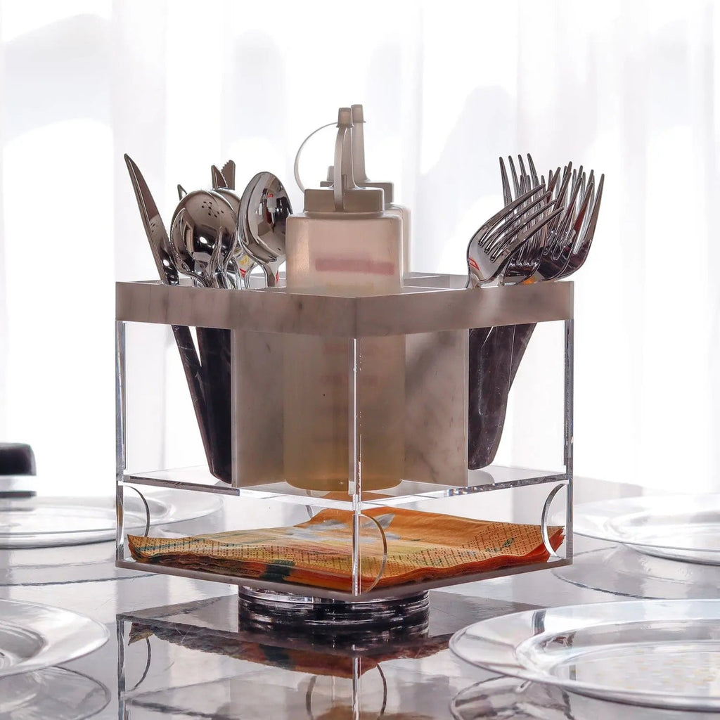 Marble swivel silverware caddy with bronze utensil holders and glass base, displaying organized flatware storage.