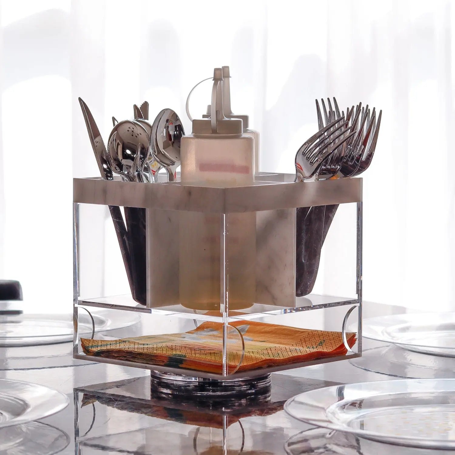 Marble swivel silverware caddy with bronze utensil holders and glass base, displaying organized flatware storage.