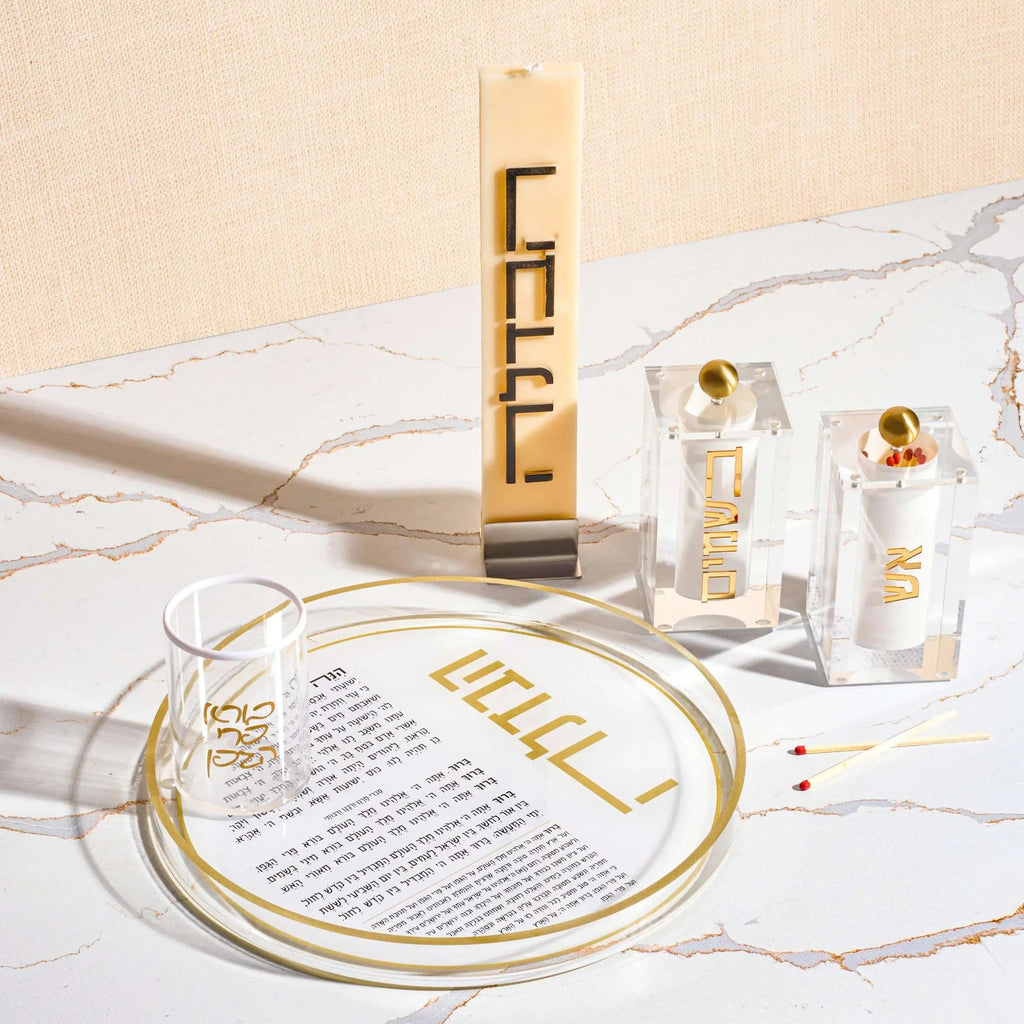 Minimalist Havdalah candle set with gold accents, including tall braided candle, matches, and circular holder on white surface