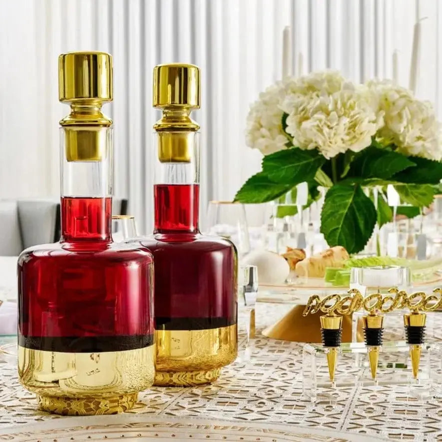 Minimalist wine decanter with red and gold tones, featuring a sleek geometric design displayed with fresh white flowers and glassware.