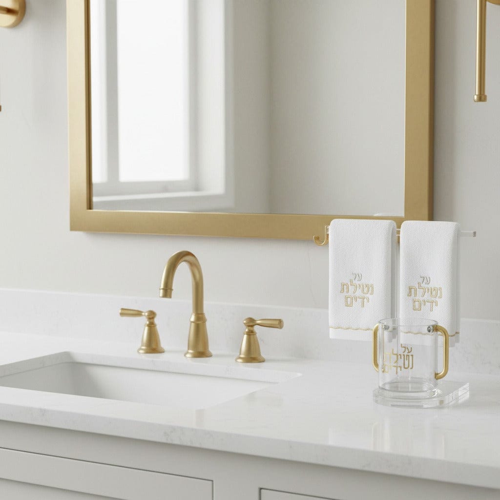 Luxury Netilat Yadayim Cup, Scalloped Towel & Stand Set. Gold-handled hand washing cup and Hebrew-embroidered towels on a clear stand in a modern bathroom - Waterdale Collection