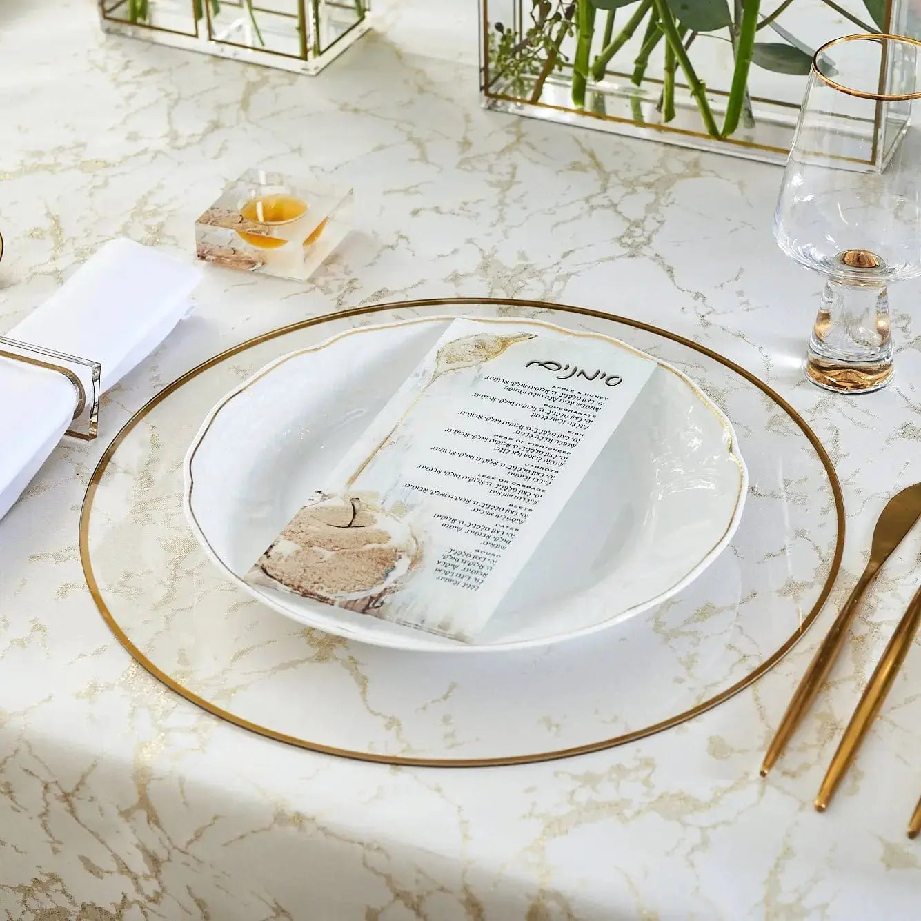 Painted Gold Simanim Card by Zelda displayed on a formal place setting with gold-rimmed charger plate and white napkin.