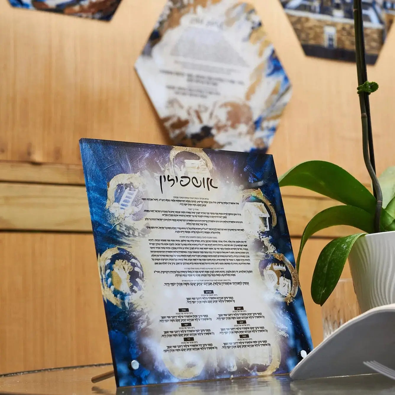 Painted Navy Tabletop Ushpizin plaque by Waterdale Collection displayed on wooden surface with plant and instructional card visible.