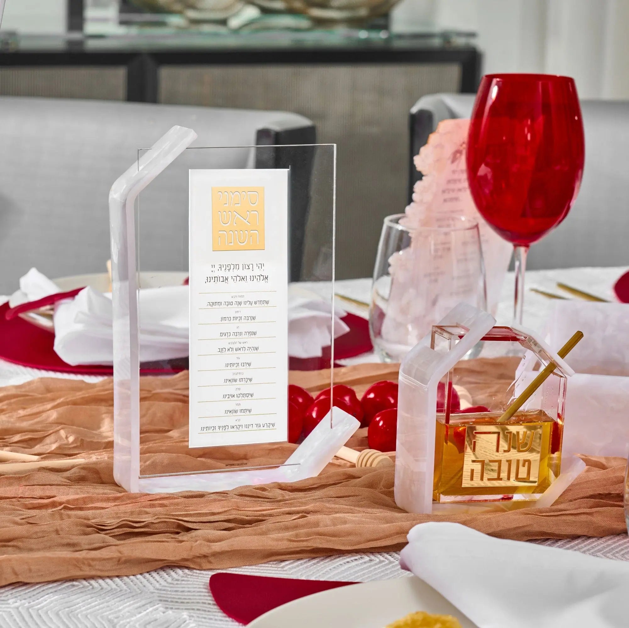 Pearlstone Simanim Tabletop lucite card in pearl marble finish, displayed on festive Rosh Hashana table setting with wine glass and decorations.