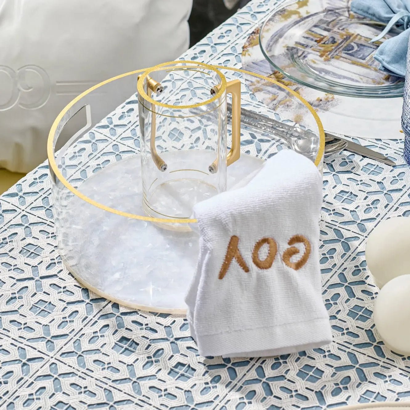 Pearlstone tall washing cup in white marble with gold accents displayed on decorative tablecloth with matching accessories
