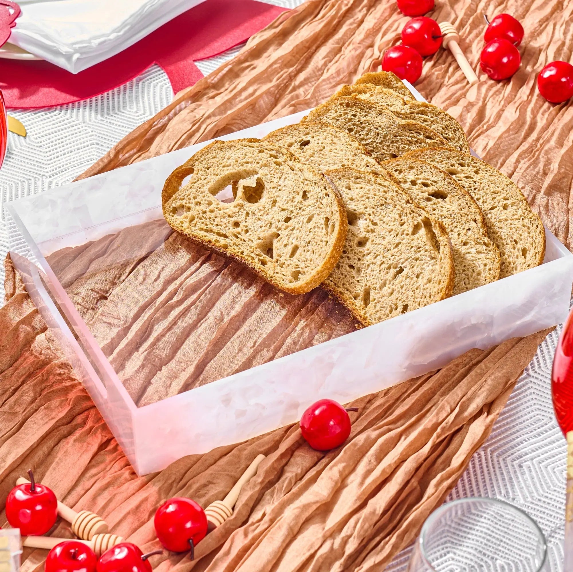 Pearlstone marble serving tray in cream and gray holding sliced bread with red currants and pink ribbon for holiday entertaining.