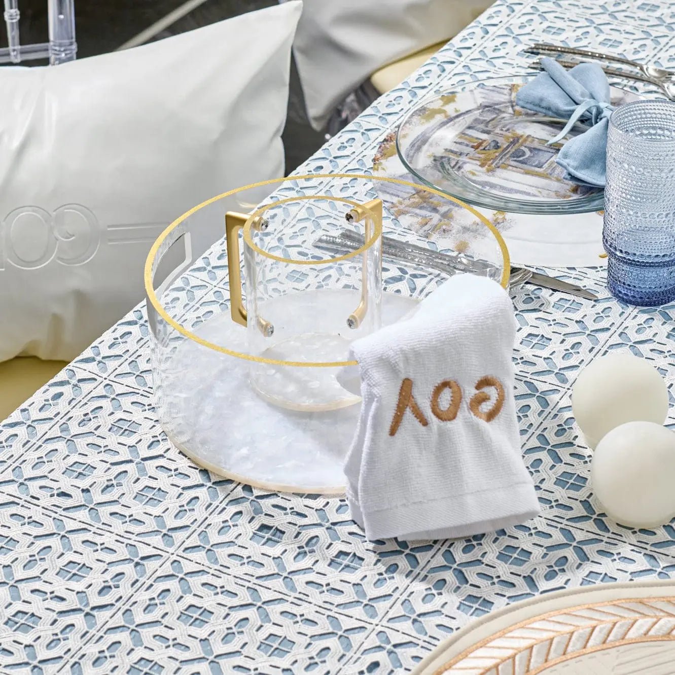 Pearlstone washing cup in white marble displayed on a textured surface with toiletries and accessories nearby, showing the cup's elegant design and practical bathroom use.